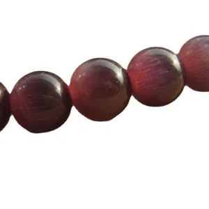 Primo piano di perle in pietra occhio di gatto viola scuro per la creazione di gioielli DIY.
