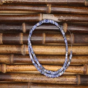 Detailopname van 4mm blauwe vierkante edelsteenkralen voor DIY-sieraden op bamboe