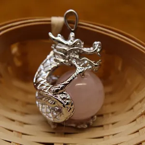 Intricate silver dragon pendant clutching pink crystal ball displayed in bamboo basket