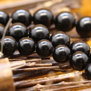 Lustrous black obsidian round loose beads for DIY jewelry making on a bamboo background