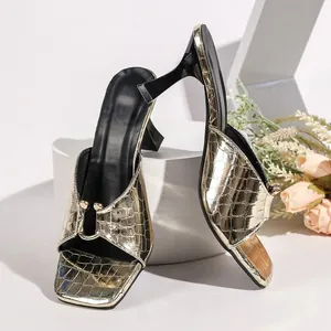 Detail view of stylish golden crocodile-pattern mules with square toe and slim high heels