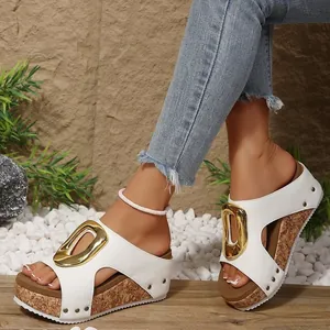 Detail shot of stylish white wedge sandals featuring a large gold buckle and cork sole