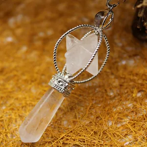 Clear quartz Merkaba star pendulum pendant with silver-toned cage on straw background