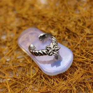 Vue détaillée d'un pendentif en forme de tong à fleur argentée sur fond bleu clair