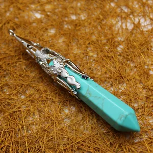 Hexagonal turquoise crystal point pendant with silver filigree cap on textured background