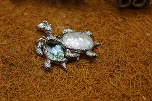 Primer plano de dos colgantes de tortuga marina con incrustaciones de concha sobre paja