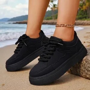 Stylish black platform sneakers for women displayed on a beautiful sunny beach background