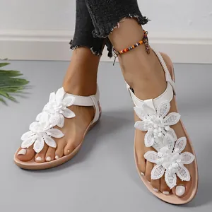 Dettaglio di sandali piatti bianchi bohémien con delicate decorazioni di fiori in pizzo