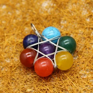 Handmade seven chakra stone flower pendant with silver wire wrap on straw background