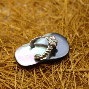 Unique flip-flop shell pendant with metallic straps on golden straw background