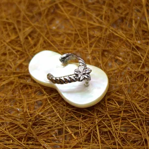 Exquisite shell flip-flop pendant with shimmering zircon flower on a rustic straw background