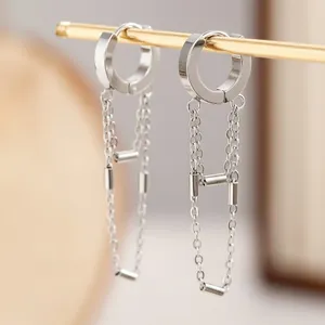 Macro view of minimalist stainless steel chain tassel earrings on a display stand.