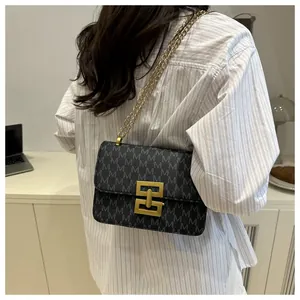 Detailed view of the monogram print and gold metal clasp on the crossbody bag.