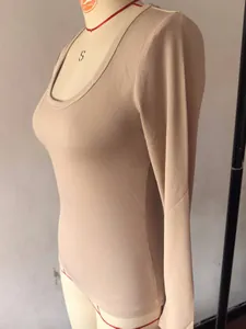 Zijaanzicht detail van een beige geribbelde nauwsluitende top met lange mouwen.