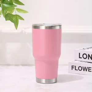 Detalle de un vaso térmico rosa de 30 oz de acero inoxidable con tapa en la mesa.