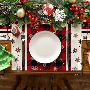 Weihnachts-Platzset mit rot-schwarzem Karomuster und Schneeflocken auf dem Tisch.