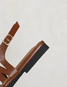 Detail view of the 2cm heel on brown leather pointed-toe sandals with gold buckle