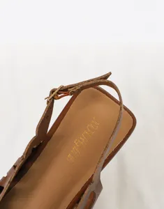 Macro detail of soft latex padded insole and buckle strap on brown vintage PU leather sandal.