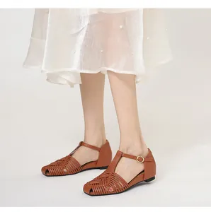 Detailed view of brown woven T-strap sandals featuring a square toe and golden buckle
