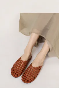 Mules trenzados marrones vintage usados por una modelo con una falda beige fluida