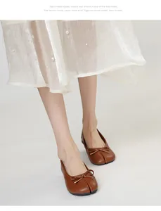 Detailed view of elegant brown split-toe Tabi flats featuring a delicate decorative bow tie