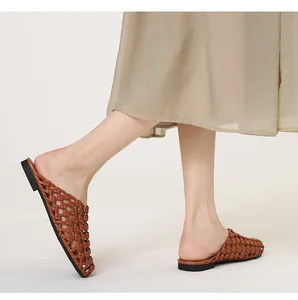 Detalle de sandalias mules trenzadas marrones vintage con falda beige muy fluida