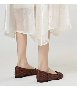 Primo piano di scarpe basse intrecciate marroni retrò con gonna bianca decorata di perle.