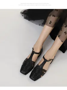 Detailed macro shot of black woven T-strap sandals with square toe and retro design style.