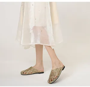 Modelo con elegantes chinelas tejidas doradas con diseño calado y suela plana cómoda