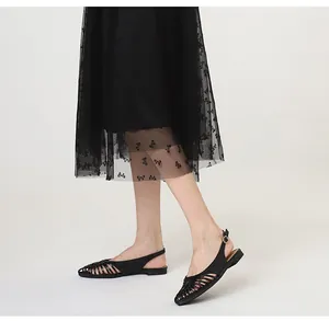 Detailed view of retro black woven flat sandals featuring pointed toe and slingback strap
