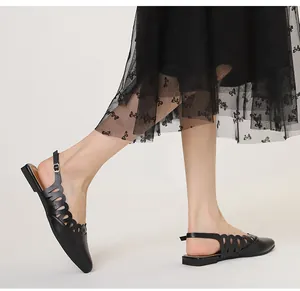 Detailed shot of black pointed-toe slingback flats with scalloped cut-out design on model