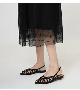 Detail shot of elegant black woven slingback flat sandals worn on a white background