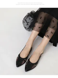Detail view of black woven pointed-toe flat sandals with slingback strap design