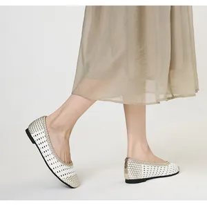 Dettaglio di ballerine intrecciate bianco e oro con design traforato traspirante su modella.
