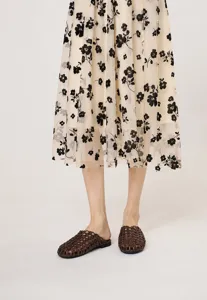 Vista detallada de mules trenzados marrón vintage combinados con falda midi de flores