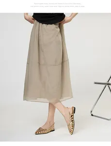 Close-up detail of gold Roman woven flat sandals paired with a stylish beige midi skirt