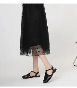 Detail view of black French retro hollow-out gladiator sandals worn with a mesh skirt.