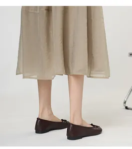 Detailed side view of dark brown leather flat Mary Janes with a delicate bow detail