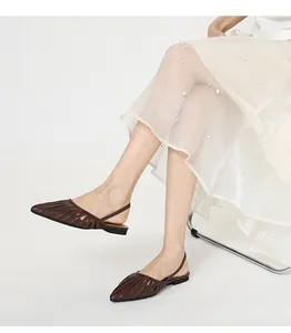 Gros plan de chaussures plates à bout pointu marron ajourées avec une jupe à perles.