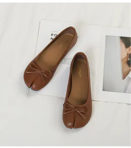 Detailed top view of brown tabi split-toe ballet flats with a bow on white background