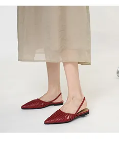 Élégantes sandales plates rouges à bout pointu et bride arrière portées par un mannequin
