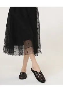 Mules negras trenzadas vintage combinadas con una falda de malla con lazos. Detalle