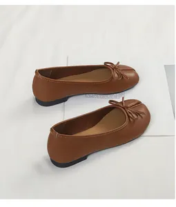 Elegant brown split-toe ballet flats with bow detail displayed on clean white props