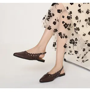 Brown pointed-toe slingback flats with decorative hollow-out pattern on model.