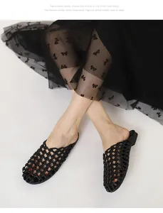 Primer plano de chinelas tejidas negras en modelo con fondo blanco minimalista