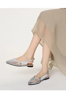 Detail view of silver woven pointed-toe slingback flats on a model wearing a skirt
