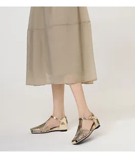 Detail view of gold woven T-strap sandals with square toe worn by a model