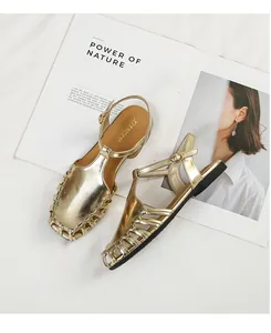 Elegant detail shot of golden French retro hollow-out Roman sandals on a magazine prop