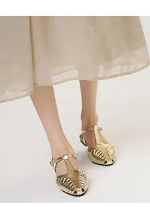 Detailed shot of golden woven T-strap flat sandals with a retro pointed toe design