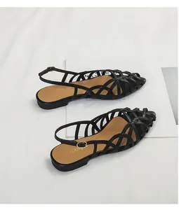 Detail showing the intricate black woven leather patterns of these flat Roman sandals.